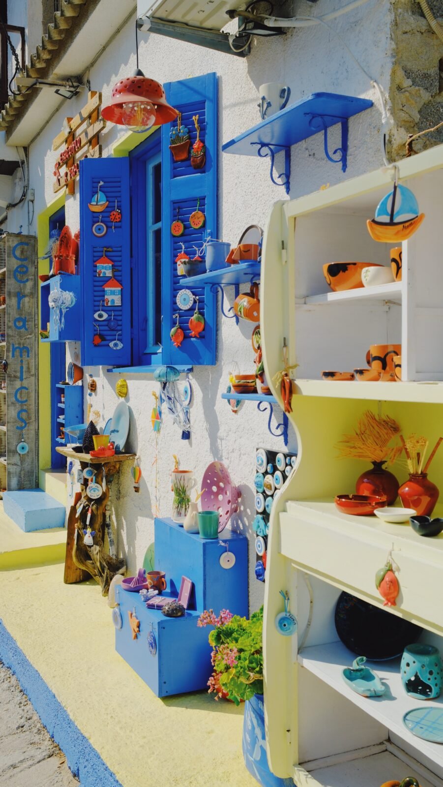 Small charming shop with blue window frames displaying handmade ceramics in Lesvos