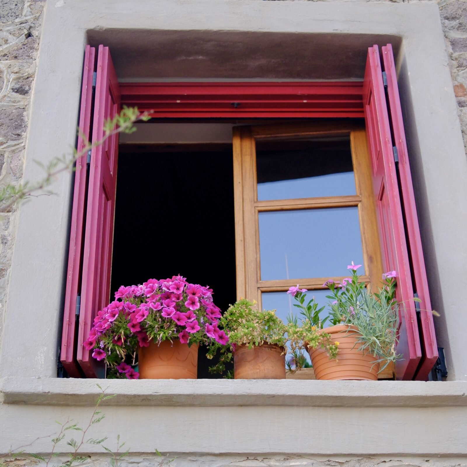 Window adorned with pink flowers on the island of Lesvos, Greece.