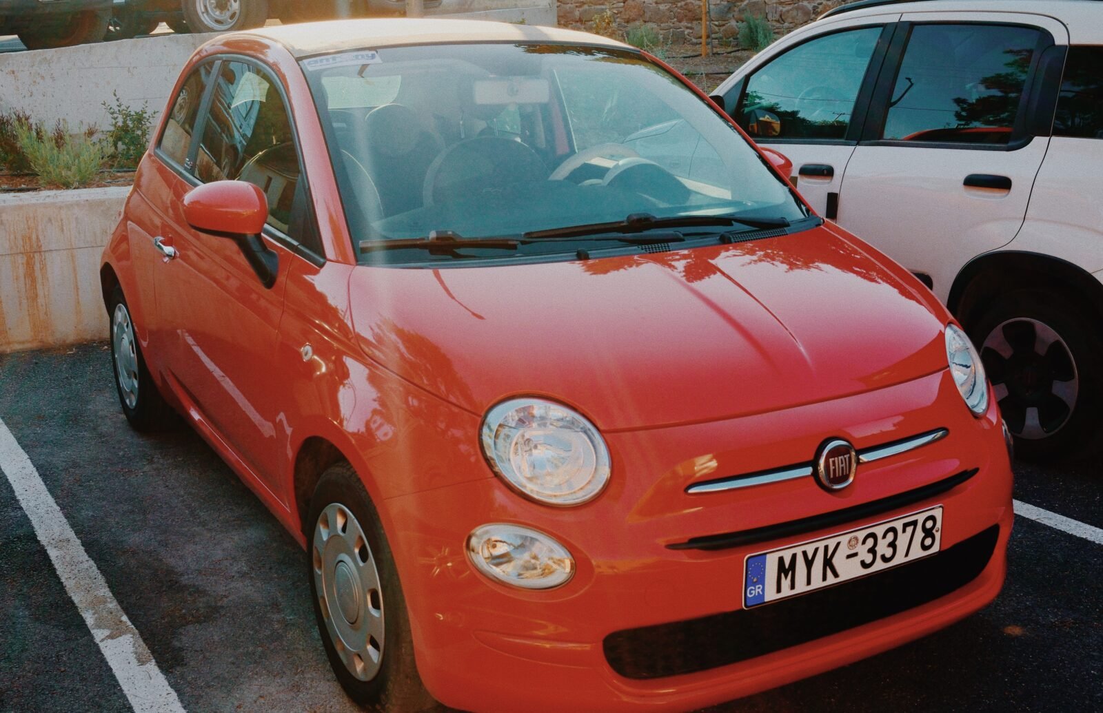 A red Fiat rental car parked by the coast