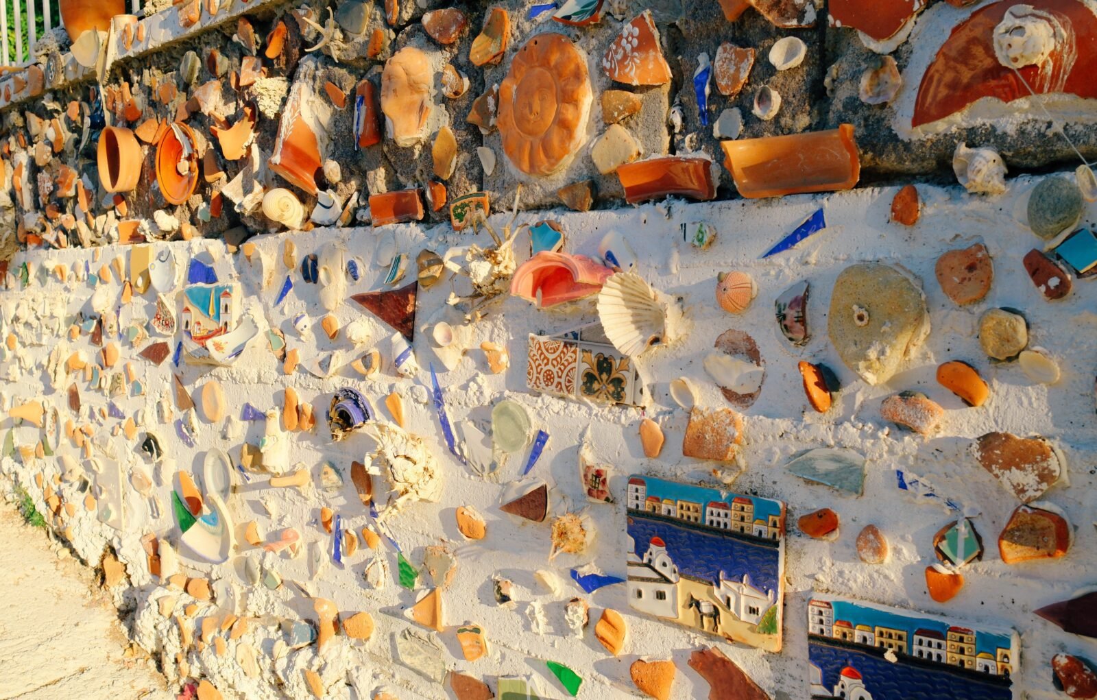 Decorative wall with seashells, glazed stones, and ceramic tiles in the village of Skala Sikamineas, Lesvos, Greece.